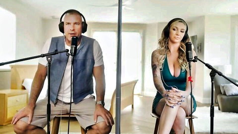 Blonde tattooed woman in green dress with man in podcast setup for Bellesa unscripted erotic scene