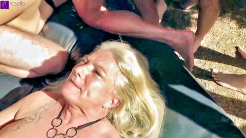 Mature blonde Nora and Rosella in outdoor group sex on beach with gang