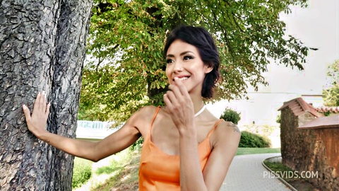 Veronica Leal smiling playfully outdoors in orange top against tree