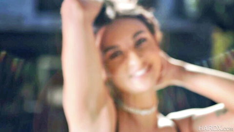 Hailey Rose smiling topless, arms raised exposing big breasts outdoors