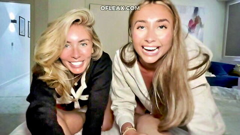 Two young blondes kneeling on bed smiling with open jackets exposing medium tits and cleavage