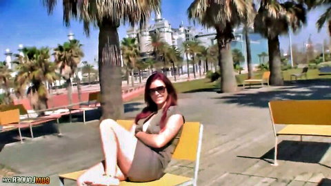 Sexy redhead in short green dress posing with legs up on yellow beach chair outdoors