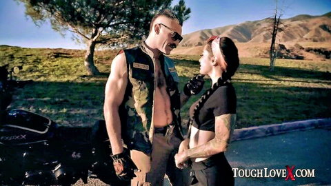 Katrina Jade with tattooed muscular biker outdoors by motorcycle