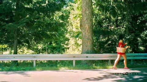Calita Fire in short red dress and heels walking outdoors with flower basket