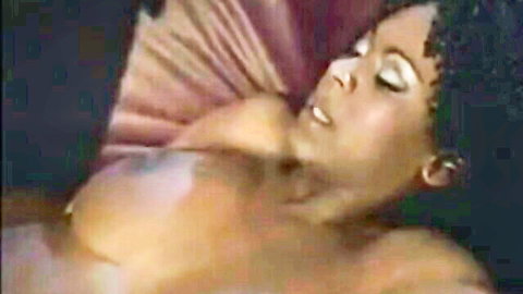 Ebony babe with massive bare tits lying back in moaning ecstasy.