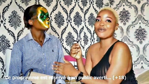 African women in adult interview, one with tribal mask, 18+ content