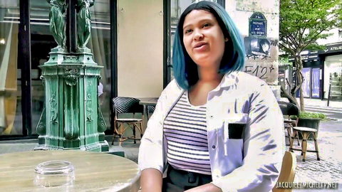 French BBW with blue hair smiling clothed at outdoor cafe table
