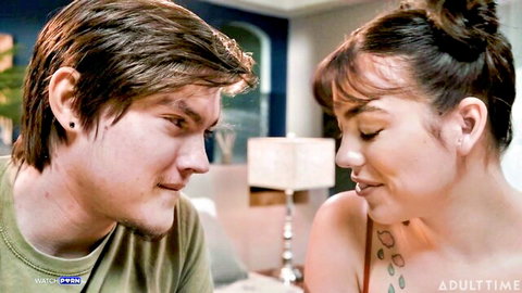 Tattooed brunette MILF with cleavage gazes lustfully at young stud in green shirt before taboo kiss