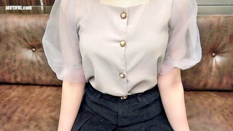 Japanese beauty in sheer blouse and tight pants sitting seductively on couch