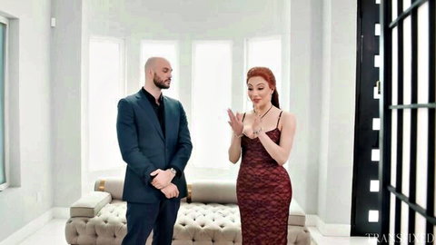 Ariel Demure in red dress gestures excitedly to bald man in suit