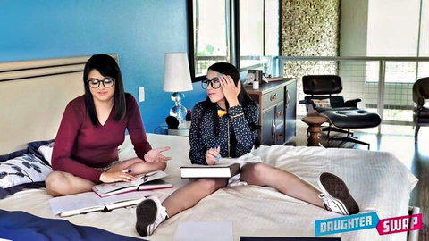 Two young brunette college girls with glasses studying on bed in daughter swap tease