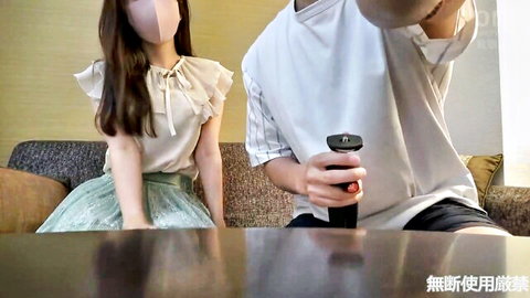 Young skinny Japanese girl in ruffled blouse and green skirt sits clothed with guy holding game controller on couch
