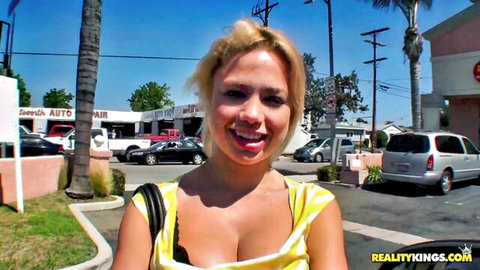 Blonde Charity Lane smiles in low-cut yellow top outdoors