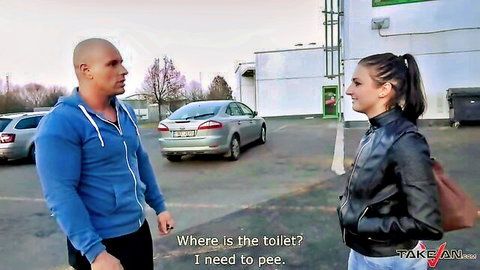 Bald muscular man asks brunette in leather jacket for toilet in parking lot