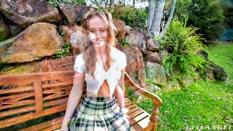 Blonde in schoolgirl plaid skirt and crop top on outdoor bench, Evil Angel