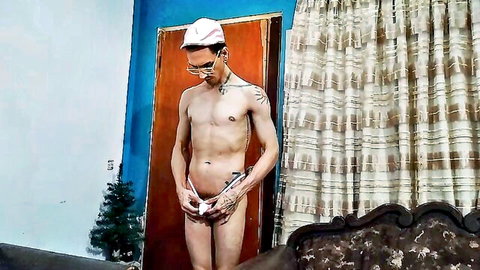 Naked tattooed man teasing with hands over crotch, wearing white holiday hat