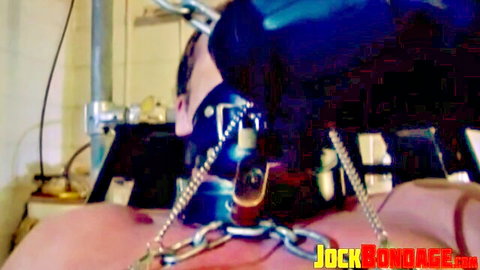 Muscular man heavily chained and hooded in intense BDSM bondage