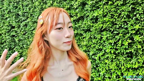 Petite Asian Thai woman with orange hair in black lingerie smiling outdoors
