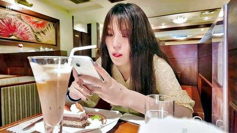 Tall Asian model in blouse sipping iced coffee at cafe, phone selfie