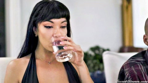Little Puck in seductive black dress sipping water with man nearby