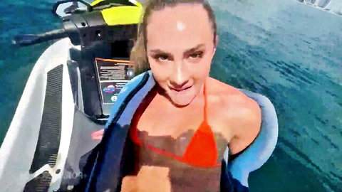 Fit woman in red bikini smiling on jetski by turquoise water