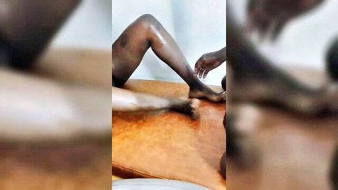 Nude Kenyan ebony woman spread on table, man caressing her foot