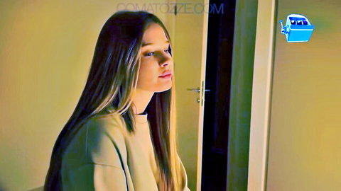 Side profile of sexy long-haired blonde in tight sweater standing by door