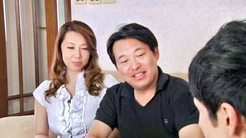Japanese brunette MILF in ruffled white blouse chats intimately with two men on couch