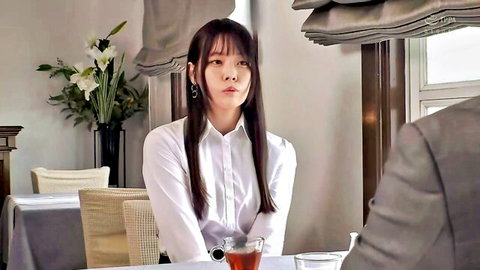 Elegant Asian woman in white shirt at table with suited man, softcore vibe
