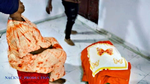 Ebony pregnant woman in orange ankara dress sitting on floor with standing man in room