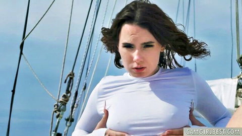 Small Italian beauty on yacht cups wet white top over breasts, wind-swept hair