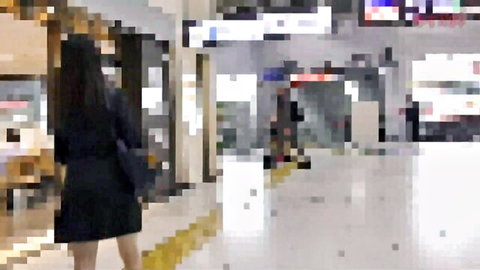 Blurry view of Asian woman in black dress walking in train station, chikan tease