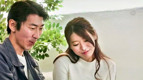 Japanese couple smiling intimately outdoors with green leaves background