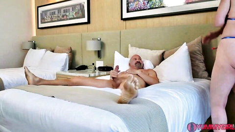 Busty topless bikini babe strokes naked man's hard cock on hotel bed