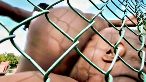 Ebony man's huge ass cheeks spread wide revealing tight asshole through chain-link fence outdoors