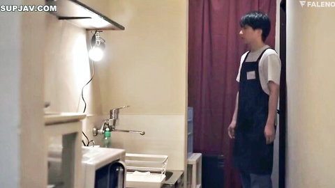 Young Japanese man in apron stands in cozy room, JAV Shelter From Storm scene