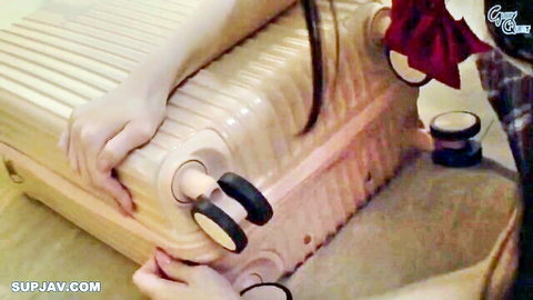 Asian woman in red bow bending over suitcase in forbidden caregiving scene