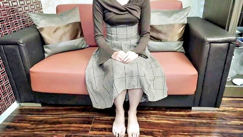 Slender Asian model in checkered skirt and top, sitting with bare feet