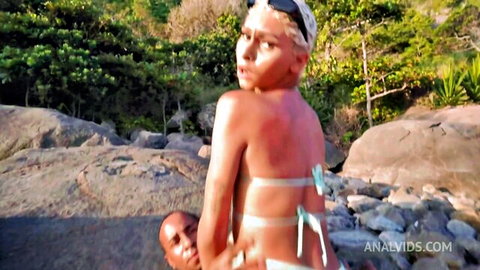 Skinny blonde teen bent over rocks outdoors as dark guy grabs her hips for beach fuck