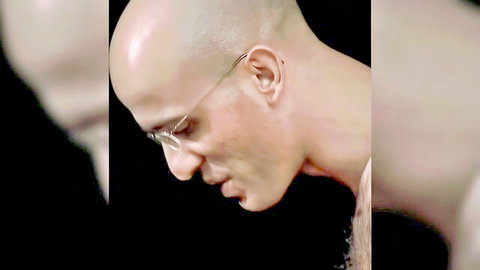 Closeup profile of bald Caucasian man in glasses looking down intensely