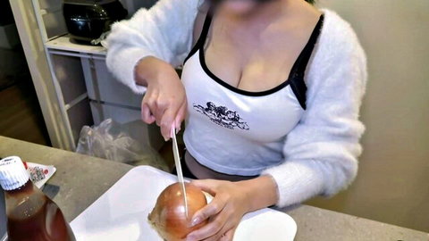 Busty Asian woman in fuzzy sleeves and low-cut top cutting onion