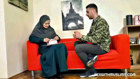 Arab hijabi MILF in green abaya sits smiling with camo boyfriend on red couch