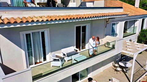 Eveline Dellai embraces lover in white robes on sunny balcony in Blacked scene