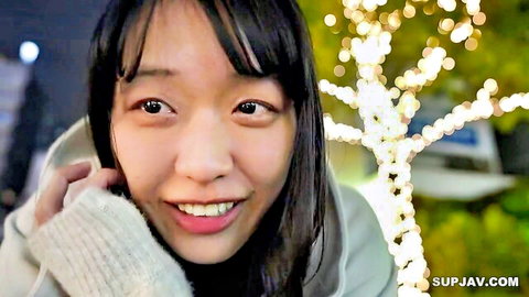 Smiling young Asian woman in hoodie under festive lights, toned JAV beauty