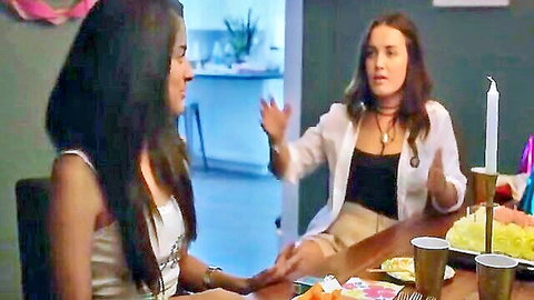 Two sexy women in casual tops chatting at birthday party table