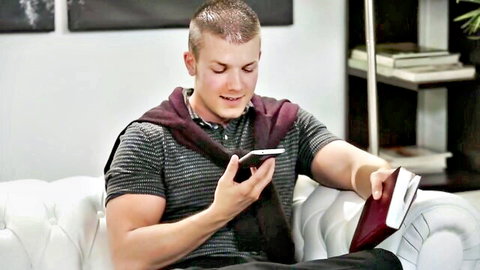 Muscular young man reading red book while checking phone, stylish casual look