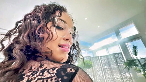 Seductive mixed-race woman with curly hair and glasses in black lace lingerie