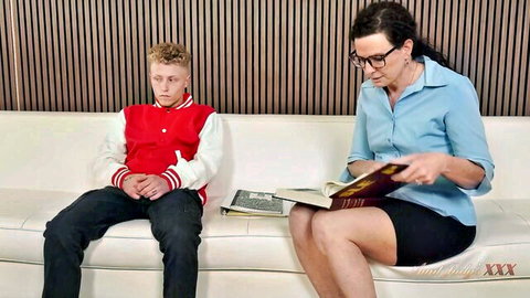 Beth McKenna as professor reading book with student on couch
