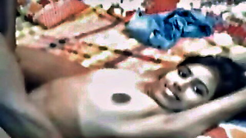 Dark-haired Bangladeshi amateur babe smiling nude on bed, exposed breasts
