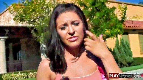 Gracie Glam looking horny in low-cut pink top, pointing playfully outdoors